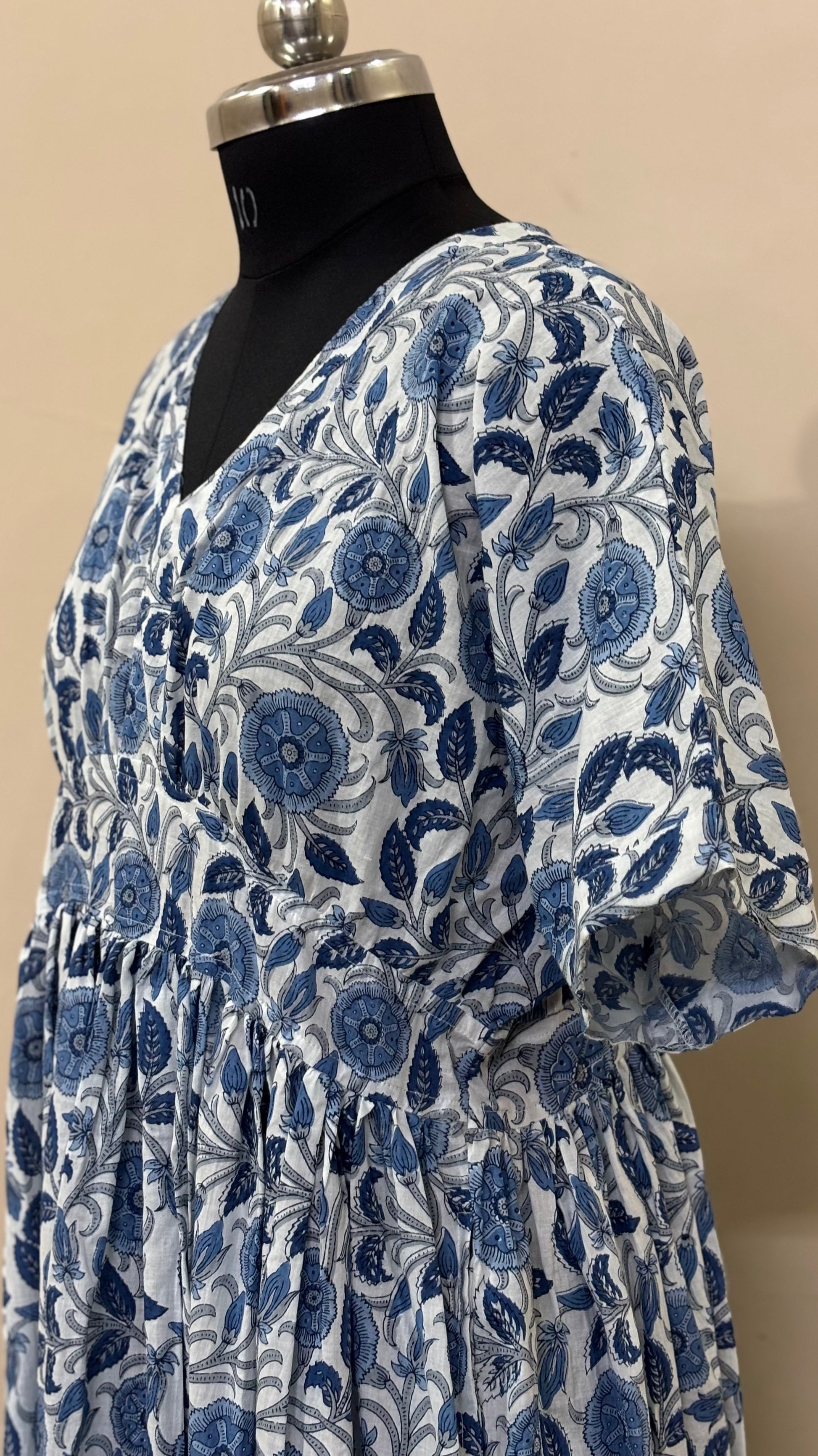 Blue and white floral dress on a mannequin against a beige background